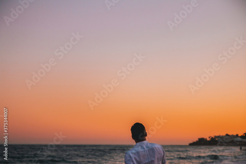 Silhouette of a man on the beach looking at sunset