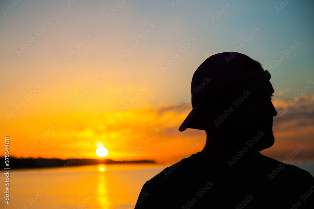 Silhouette of a man in the sunny day on the beach with turquoise sea behind him Silhouette of a man in the sunny day on the beach with turquoise sea behind him