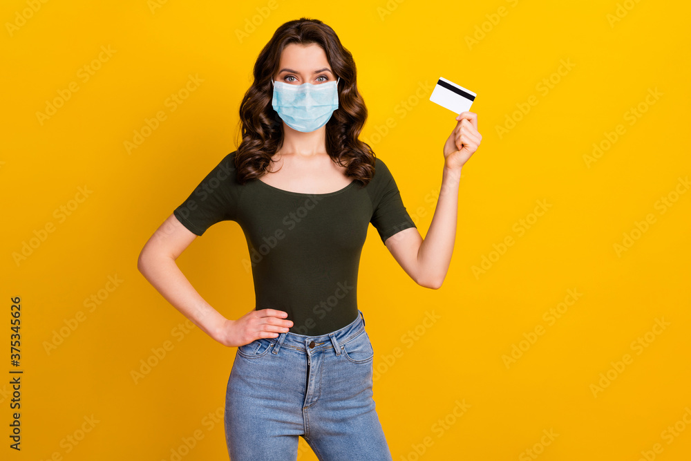 Portrait of her she nice attractive healthy wavy-haired girl wear safety gauze mask holding hand bank card stop mers cov pandemia stay home isolated bright vivid shine vibrant yellow color background Portrait of her she nice attractive healthy wavy-haired girl wear safety gauze mask holding hand bank card stop mers cov pandemia stay home isolated bright vivid shine vibrant yellow color background