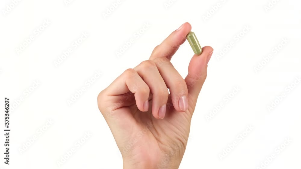 female hand holds in fingers capsule superfoods moringa or spirulina female hand holds in fingers capsule superfoods moringa or spirulina