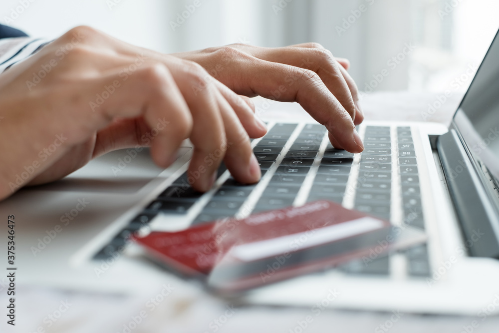 The businesswoman's hand is holding a credit card and using a laptop for online shopping and internet payment in the office The businesswoman's hand is holding a credit card and using a laptop for online shopping and internet payment in the office
