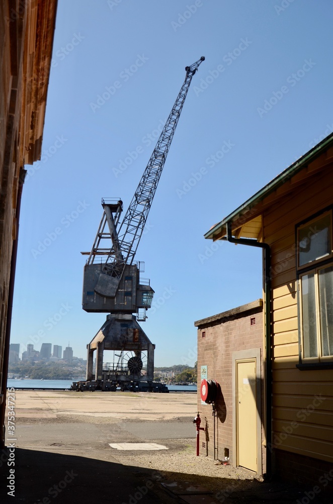 Old rusted industrial crane with wheels, viewed between two buildings on Cockatoo Island, Sydney, Australia