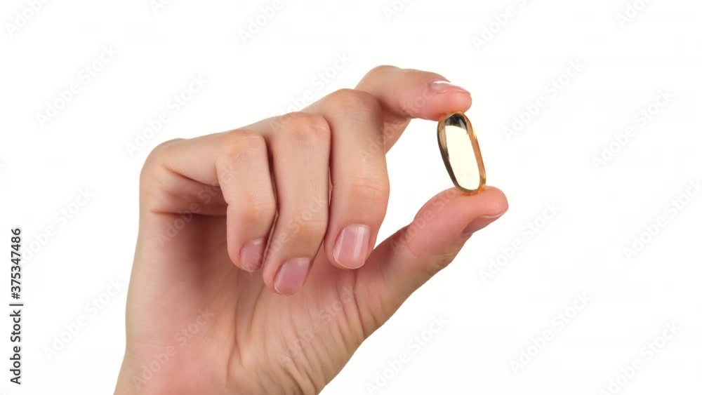 female hand holds in fingers capsule of Omega 3. Omega 3 gold fish oil capsule female hand holds in fingers capsule of Omega 3. Omega 3 gold fish oil capsule