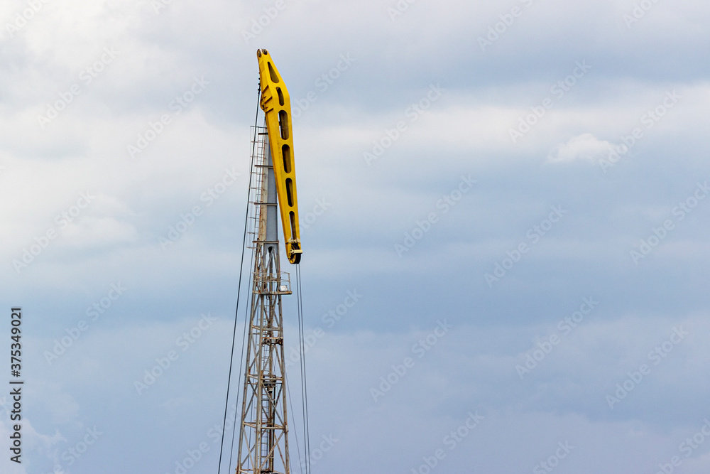 large yellow construction crane on cloudy sky background. building technology and mechanical equipment. large yellow construction crane on cloudy sky background. building technology and mechanical equipment.