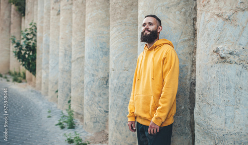 City portrait of handsome hipster guy with beard wearing yellow blank hoodie or sweatshirt with space for your logo or design. Mockup for print © San4ezz007