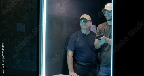 Young man practicing in shooting gallery with instructor