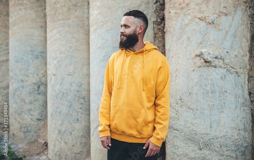 City portrait of handsome hipster guy with beard wearing yellow blank hoodie or sweatshirt with space for your logo or design. Mockup for print © San4ezz007