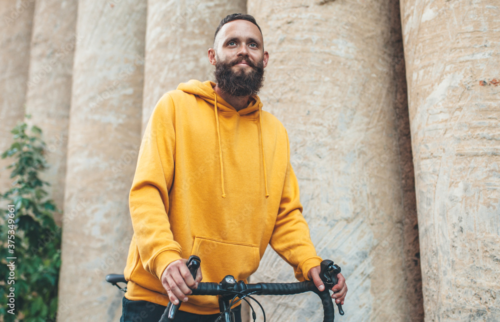 City portrait of handsome hipster guy with beard wearing yellow blank hoodie or sweatshirt with space for your logo or design. Mockup for print