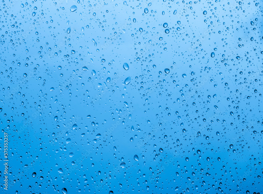 blue rain water drops on a window glass close up with sad clouds in background, drop macro texture ; bad weather backdrop blue rain water drops on a window glass close up with sad clouds in background, drop macro texture ; bad weather backdrop