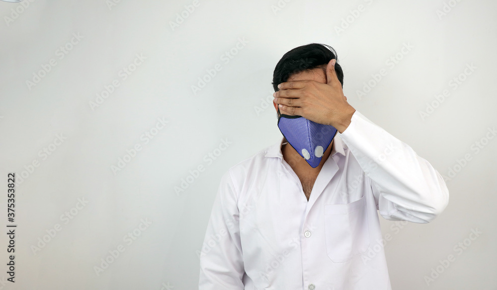 a male medical professional in white coat and mask in white background. stressed out doctor hiding identity. concept image for viral infection a male medical professional in white coat and mask in white background. stressed out doctor hiding identity. concept image for viral infection