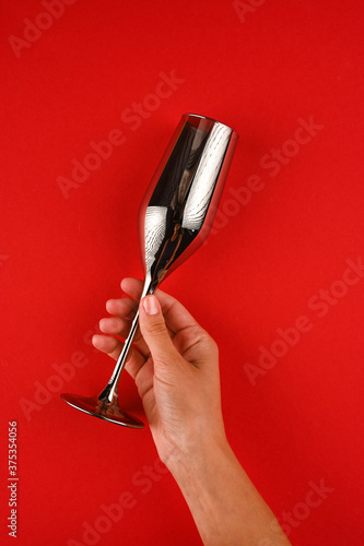 Woman hand holding silver glass of champagne isolated on red.