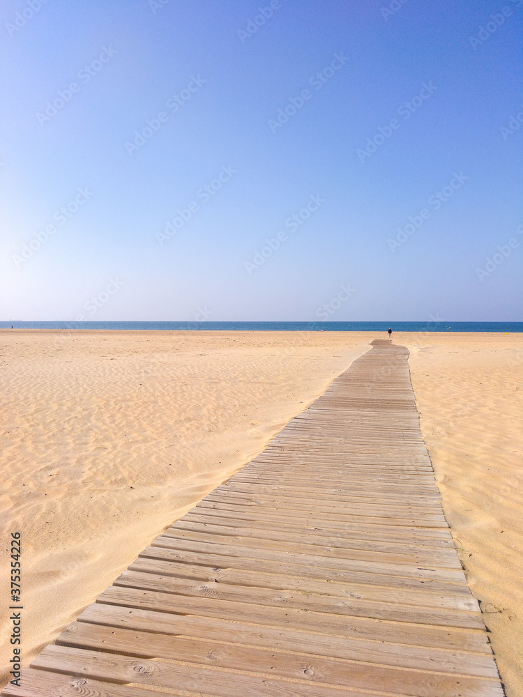 Amanecer en la playa con camino de madera.