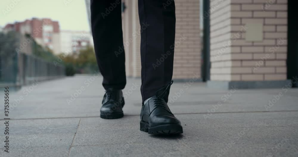 Cropped front view of businessman feet in black leather shoes and formal clothes walking outdoors, making steps, commuting to work. Cropped front view of businessman feet in black leather shoes and formal clothes walking outdoors, making steps, commuting to work.