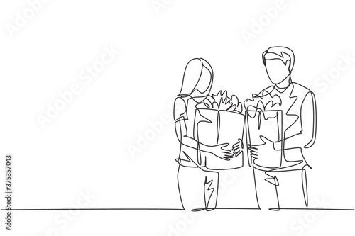 Single continuous line drawing young happy couple holding grocery paper bag after shopping at grocery store together. Buying daily goods concept. One line draw vector graphic design illustration