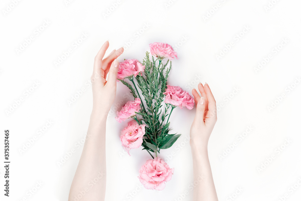 Delicate female hands frame the scattered pink buds of eustoma. White background. Flat lay. The skin is albino. The concept of Floristics and tenderness