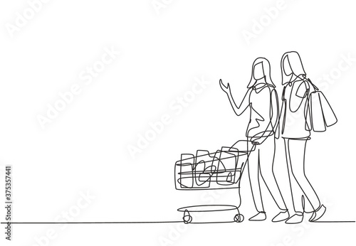 One continuous line drawing two happy friend women pushing trolley and holding paper bags when shopping together at super market. Shopping in hypermarket concept. Single line draw design illustration