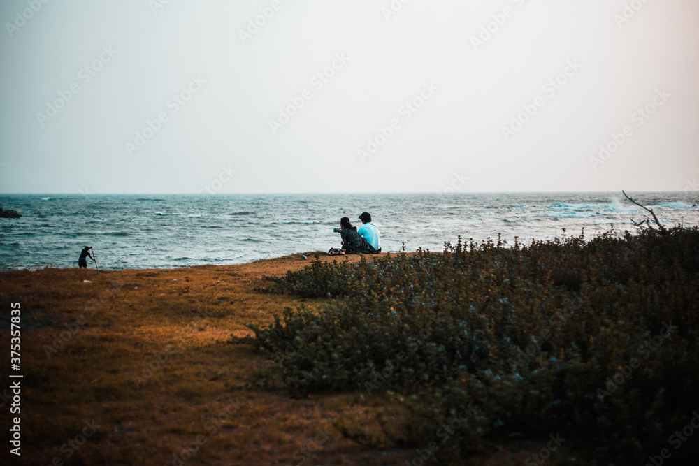 A couple of lovers sitting on a cliff near the sea