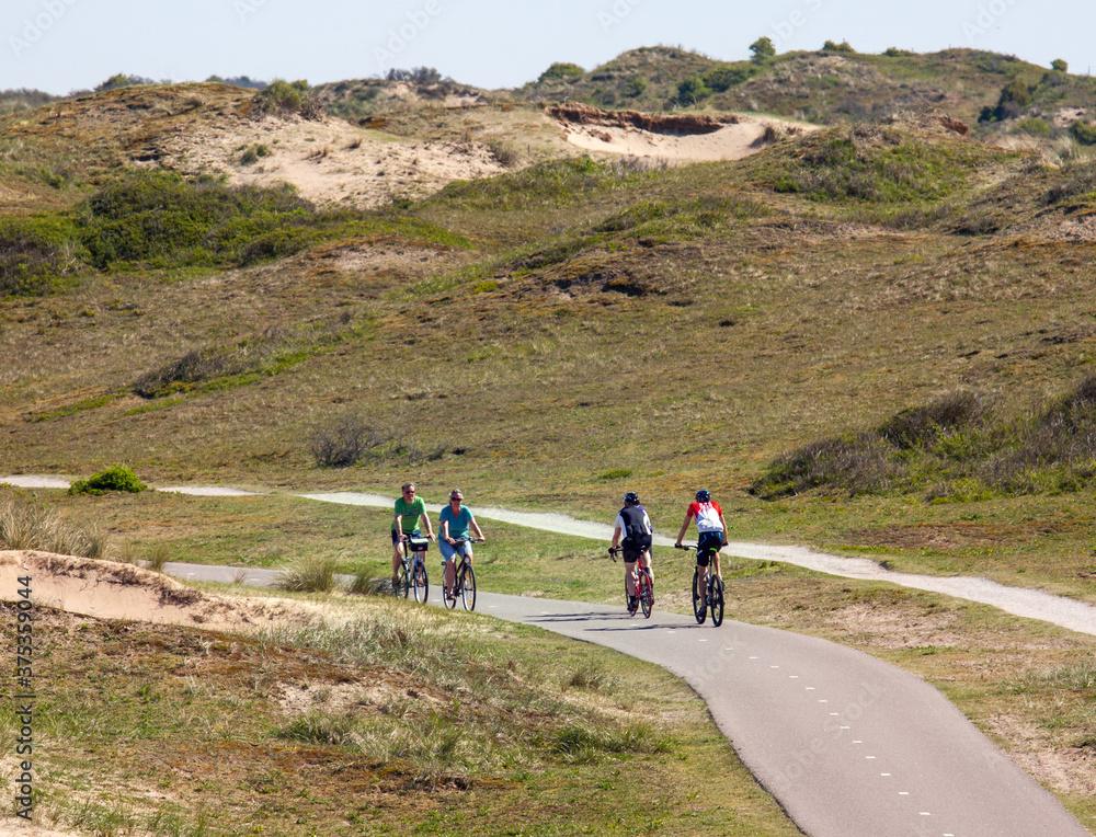 People cycling on a sunny sunday morning in the coastal dunes of Holland
