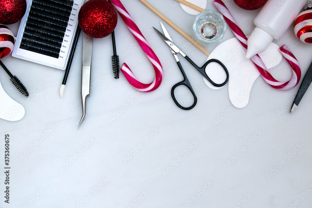 Beauty salon tools and equipment for eyelash extensions creating a frame on a white background with Christmas decorations.  Christmas background with copy space