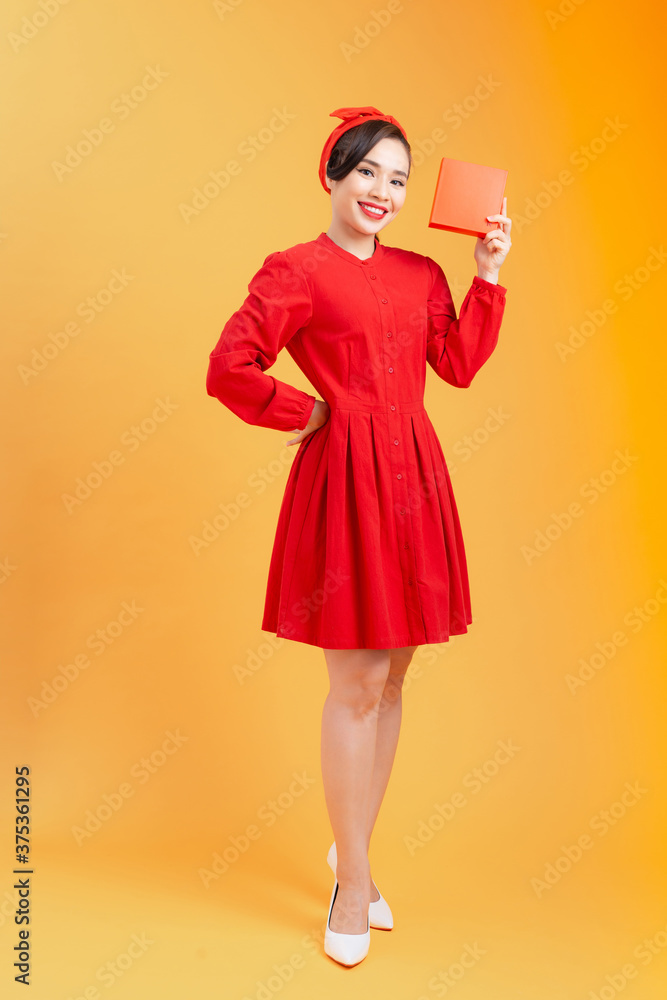 Happy young Asian woman showing gift box over orange background. Birthday, christmas, holiday, anniversary concept. Happy young Asian woman showing gift box over orange background. Birthday, christmas, holiday, anniversary concept.