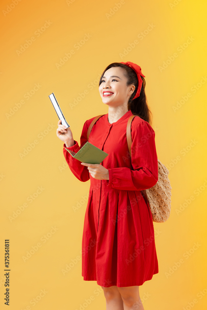 Happy young woman holding tickets and passport to travel isolated on orange background. Happy young woman holding tickets and passport to travel isolated on orange background.