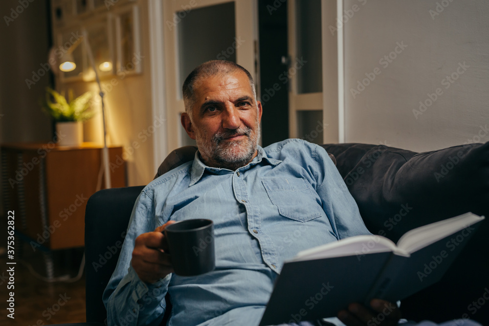 middle aged man sitting sofa reading book at home middle aged man sitting sofa reading book at home