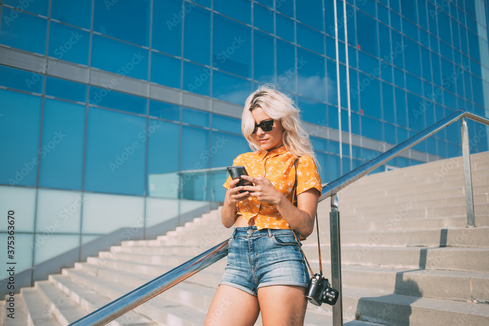 Youthful amateur photographer with camera reading article with advices for creating media content, millennial hipster girl in sunglasses installing filter application for editing photo pictures Youthful amateur photographer with camera reading article with advices for creating media content, millennial hipster girl in sunglasses installing filter application for editing photo pictures