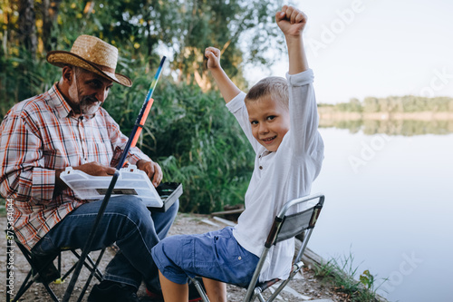 grandfather and grandson fishing outdoor on the lake