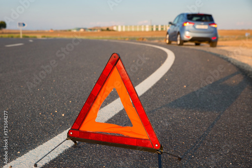 Triángulo de emergencia en la carretera avisa de un vehículo parado en la vía pública photo