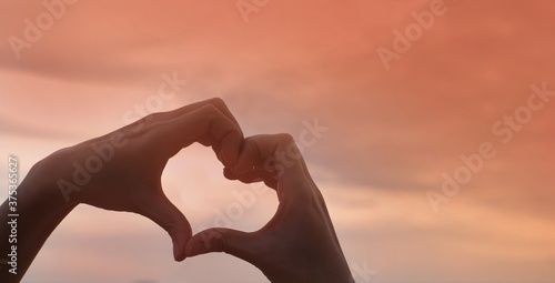 hand holding a heart on sunset background 