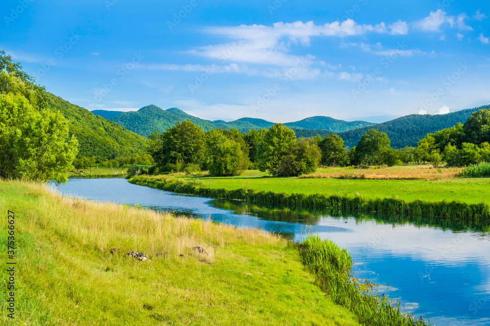 Gacka river flowing between green fields in Lika region of Croatia, beautiful landscape Gacka river flowing between green fields in Lika region of Croatia, beautiful landscape