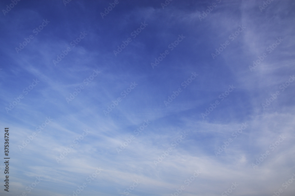 Light cirrus clouds in the deep blue sky. Typical signs of weather change. Natural background for graphic projects. Light cirrus clouds in the deep blue sky. Typical signs of weather change. Natural background for graphic projects.