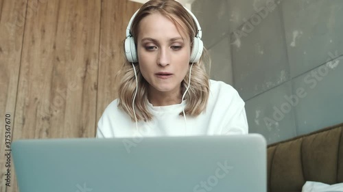 Wallpaper Mural A happy young woman with headphones is listening the music using her laptop computer sitting on the bed at home Torontodigital.ca