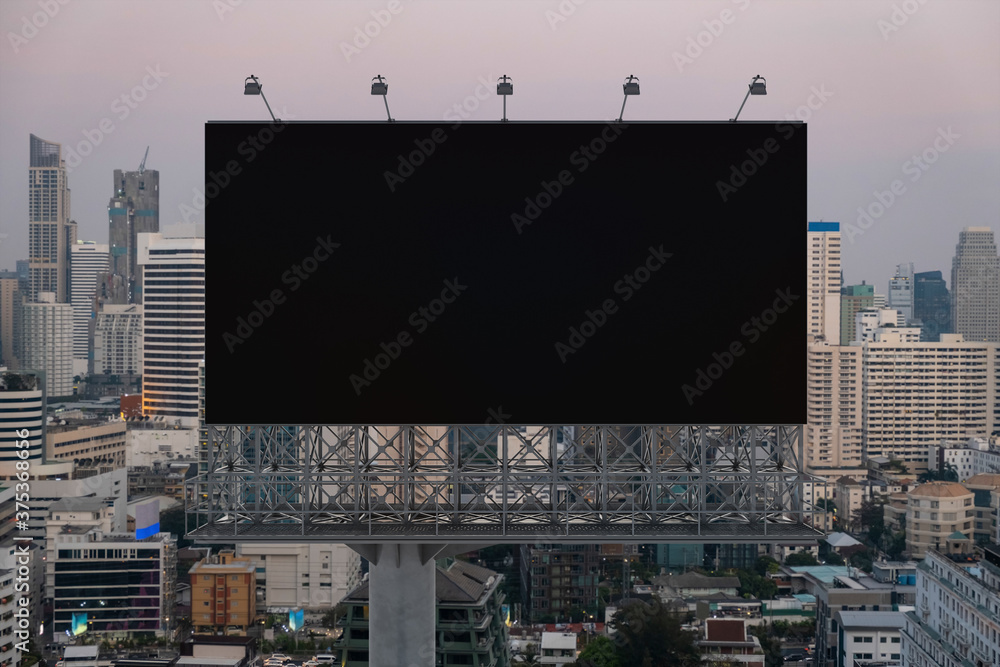 Blank black road billboard with Bangkok cityscape background at sunset. Street advertising poster, mock up, 3D rendering. Front view. The concept of marketing communication to promote or sell idea.