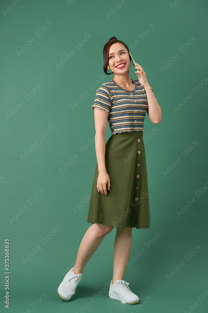 Full length portrait of a happy young woman talking on the phone isolated Full length portrait of a happy young woman talking on the phone isolated