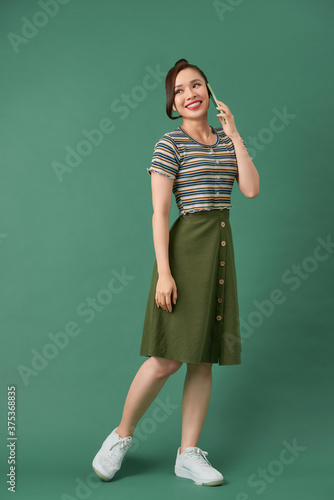 Full length portrait of a happy young woman talking on the phone isolated
