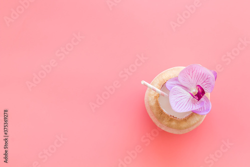 Raw coconut water or milk with straw and orchid flower, above view