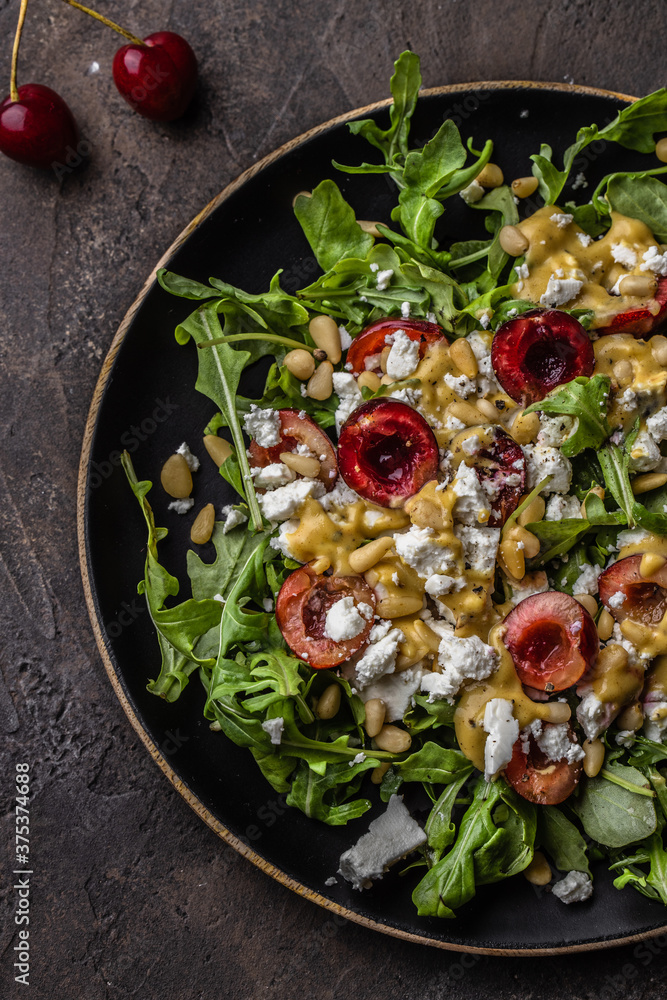 Salad with arugula, cherries, goat cheese, pine nuts, mustard -olive oil dressing
