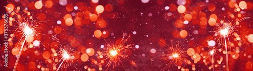 Silvester   new year background banner panorama long- Golden firework sparklers  snowflakes snow and bokeh lights on rustic dark red abstract texture