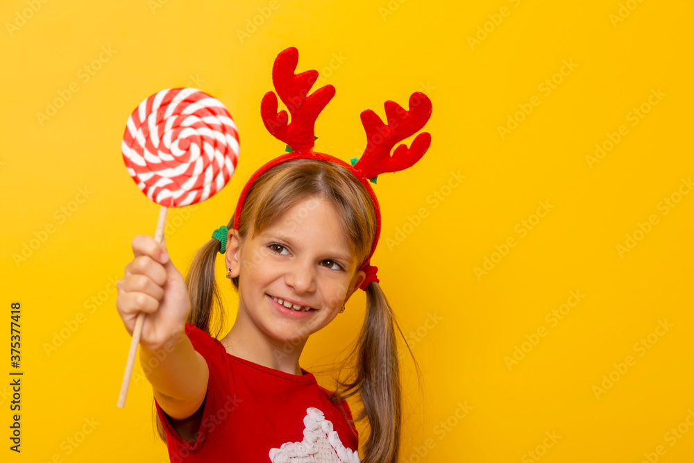Little girl wearing deer antlers costume holding lollipop