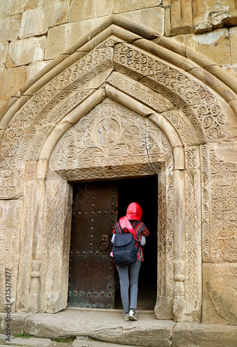 Female Traveler in Head Covering at the Entrance to the Church of the Assumption in Ananuri Castle Complex, Aragvi River Bank, Georgia © jobi_pro