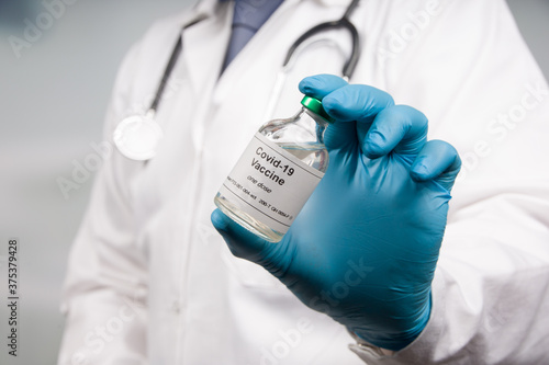 Close up of doctor's hand in medical gloves with a Covid-19 vaccine bottle photo