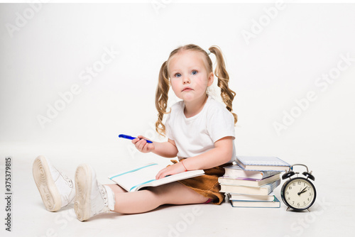 Little girl laying on the floor and drawing pictures in a notebook on white background