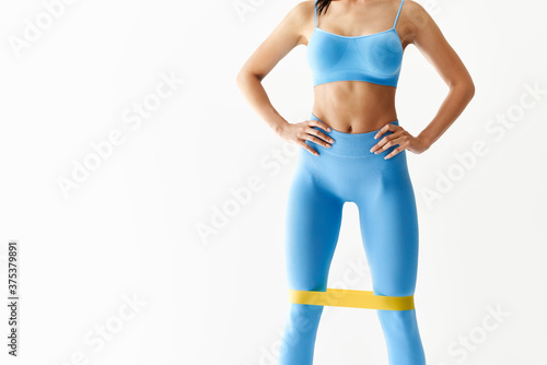 Fototapeta Sporty woman with resistance band loop workouts on white background with copy sp