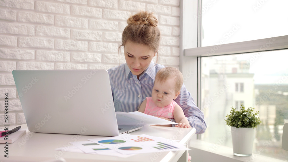 Woman with baby not concentrated at work. Business mother looking documents Woman with baby not concentrated at work. Business mother looking documents
