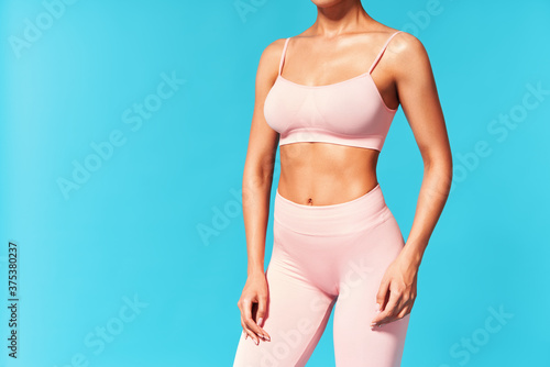 Принти на полотні Cropped image of fit woman torso on blue background with copy space