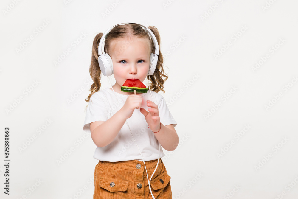 Portrait of young child girl in headset eat candy on white background Portrait of young child girl in headset eat candy on white background