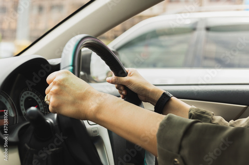 Female hands on the steering wheel of a car while driving on the road.