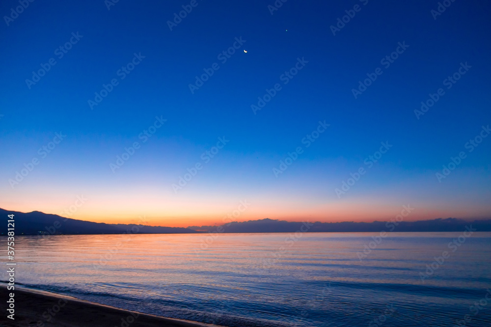 Fototapeta premium Dawn of the sun at sea. The rising sun behind the mountains. Kyrgyzstan.