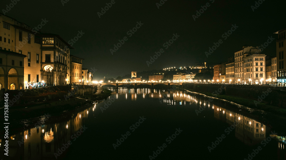 View of European city with bridge and reflections on the water of builds and city lights by night.